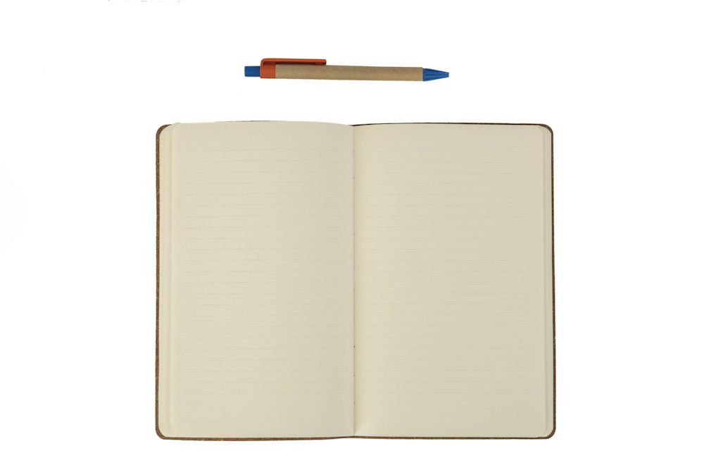 白い背景に置かれたノートと鉛筆。ゴールを書き出す作業のイメージ